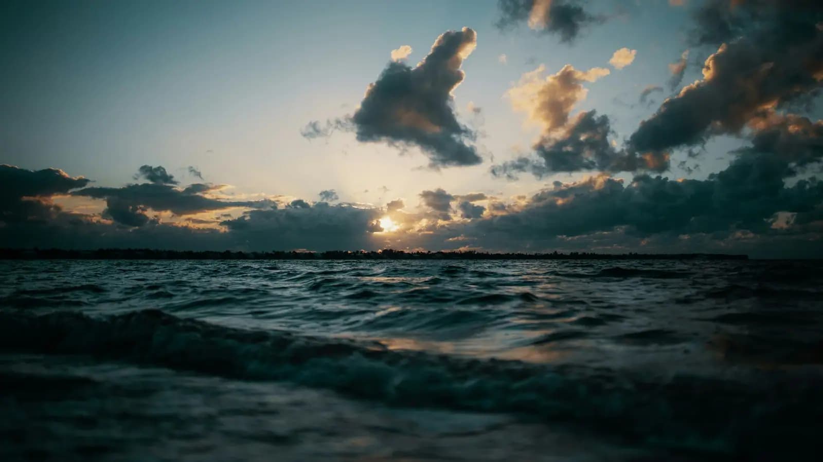 The sun setting over open water off Sanibel Island with a band of low cloud on the horizon
